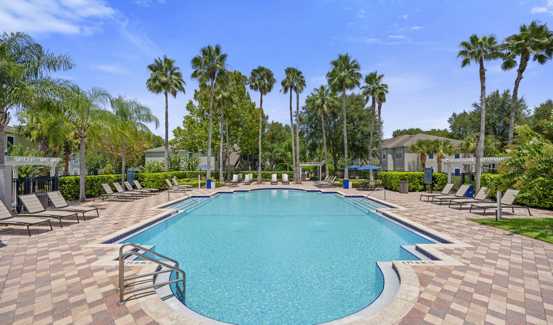 Relax and unwind poolside a pool with trees around it